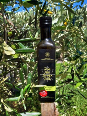 A picture of the Down the Garden Path olive oil standing on a post in front of an olive tree. 