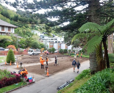 An image of the Welllington Botanic Garden Display Garden beds that are just soil with staff working on them with rakes. 