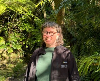 Gardener Fleur smiling surrounded by native bush. 